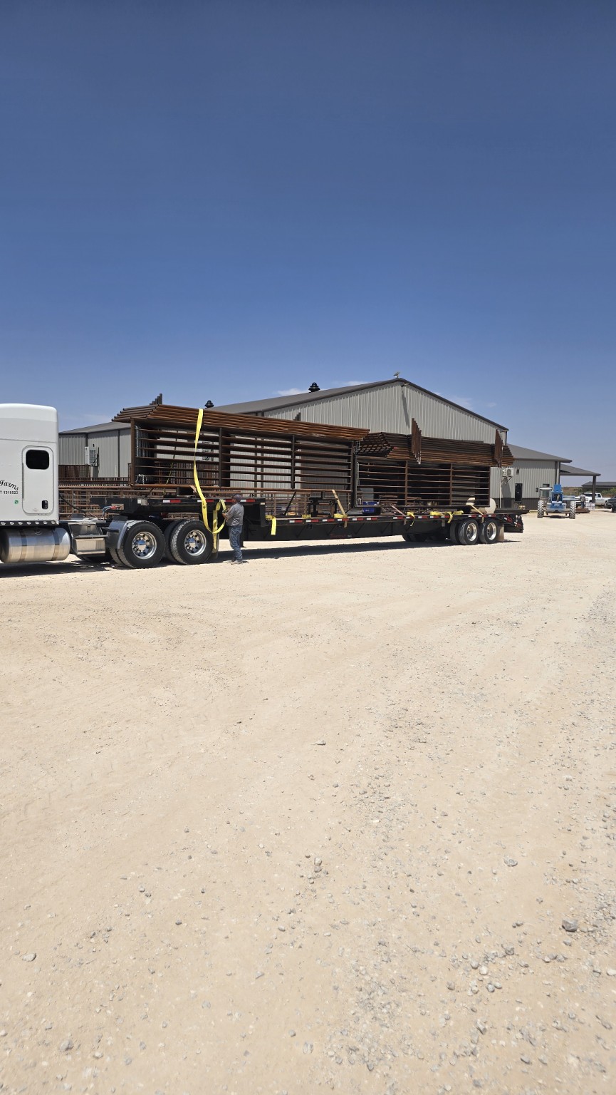 Long flatbed load of ranch equipment outside the shop